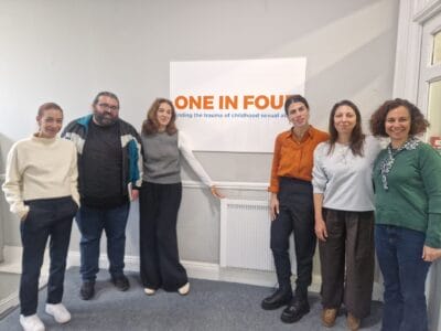5 women and one man standing in front of a sign on a wall that says 